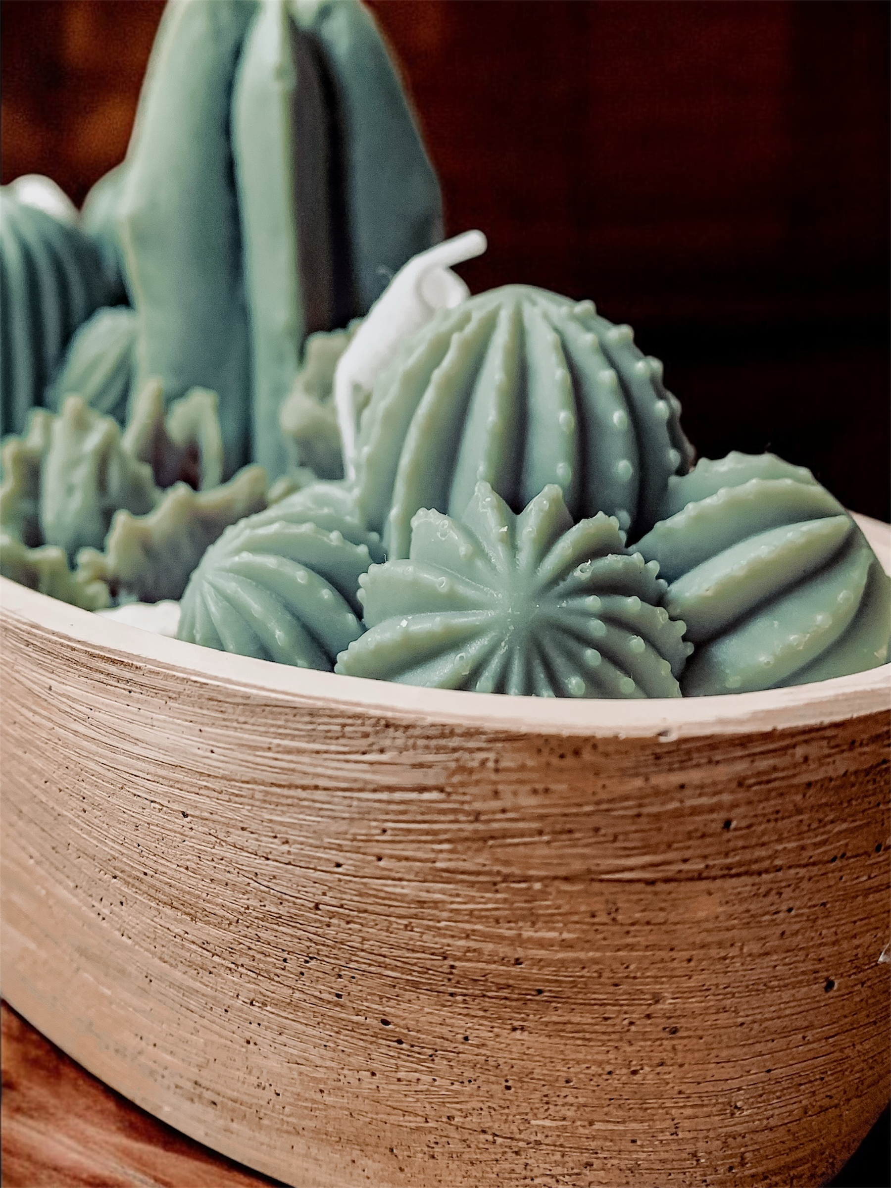 Dekoracyjna świeca Kaktus Glow w postarzanym, brązowym pojemniku z kaktusami i grysem marmurowym.