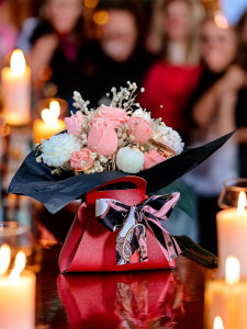 Flower Box dekoracyjna świeca sojowa z małymi różowymi i kremowymi kwiatkami. W czerwonej torebce z kokardą i czarnym akcentem. Z lampkami led.