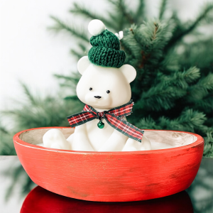 Świeca sojowa Ice Bear dekoracja na świeta, w czerwonym pojemniku biały miś w zielonej czapce z szalikiem w kratkę i dzwoneczkiem.