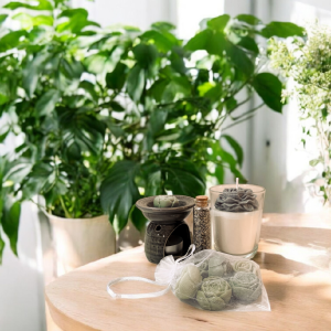 Zestaw ze świecą sojową kominkiem i lawendą. Zestaw składa się z szarego kominka na woski, woski w kształcie kwiatków i suszoną lawenę w szklanej butelce.