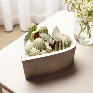 Dekoracyjna świeca Serce z kaktusami - pojemnik pastelowy w kształcie serca, trzy zielone kaktusy z dekoracyjnym motylem. Knot drewniany.