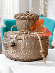 Jesienne Żołędzie świeca w brązowym pojemniku z pokrywką. Ozdobiona dużym brązowym żołędziem i jesiennym liściem, przywiązanym sznurkiem jutowym.