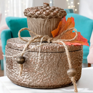Jesienne Żołędzie świeca w brązowym pojemniku z pokrywką. Ozdobiona dużym brązowym żołędziem i jesiennym liściem, przywiązanym sznurkiem jutowym.