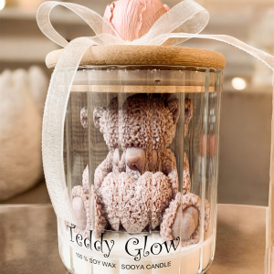 Teddy Glow świeca sojowa w szklanym ryflowanym pojemniku brązowy miś z wosku sojowego, z piwonią i kokardką na pokrywce.