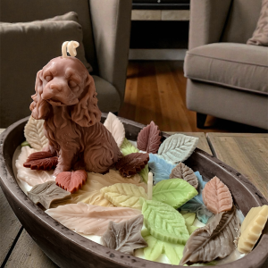 Świeca sojowa z pieskiem w kolorowych liściach w pastelowym pojemniku.