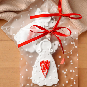 Zawieszka aniołek z sercem – upominek dla gości na wesele, komunię, urodziny, zapakowany w przezroczysty woreczek z czerwoną kokardką.