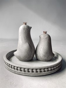 Betonowa taca z ptaszkami z betonu w szarym kolorze i złotymi koronami.