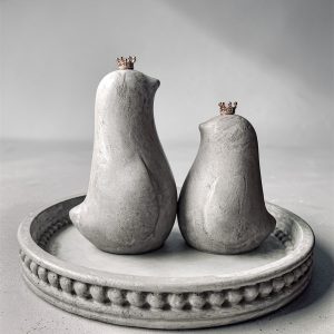 Betonowa taca z ptaszkami z betonu w szarym kolorze i złotymi koronami.